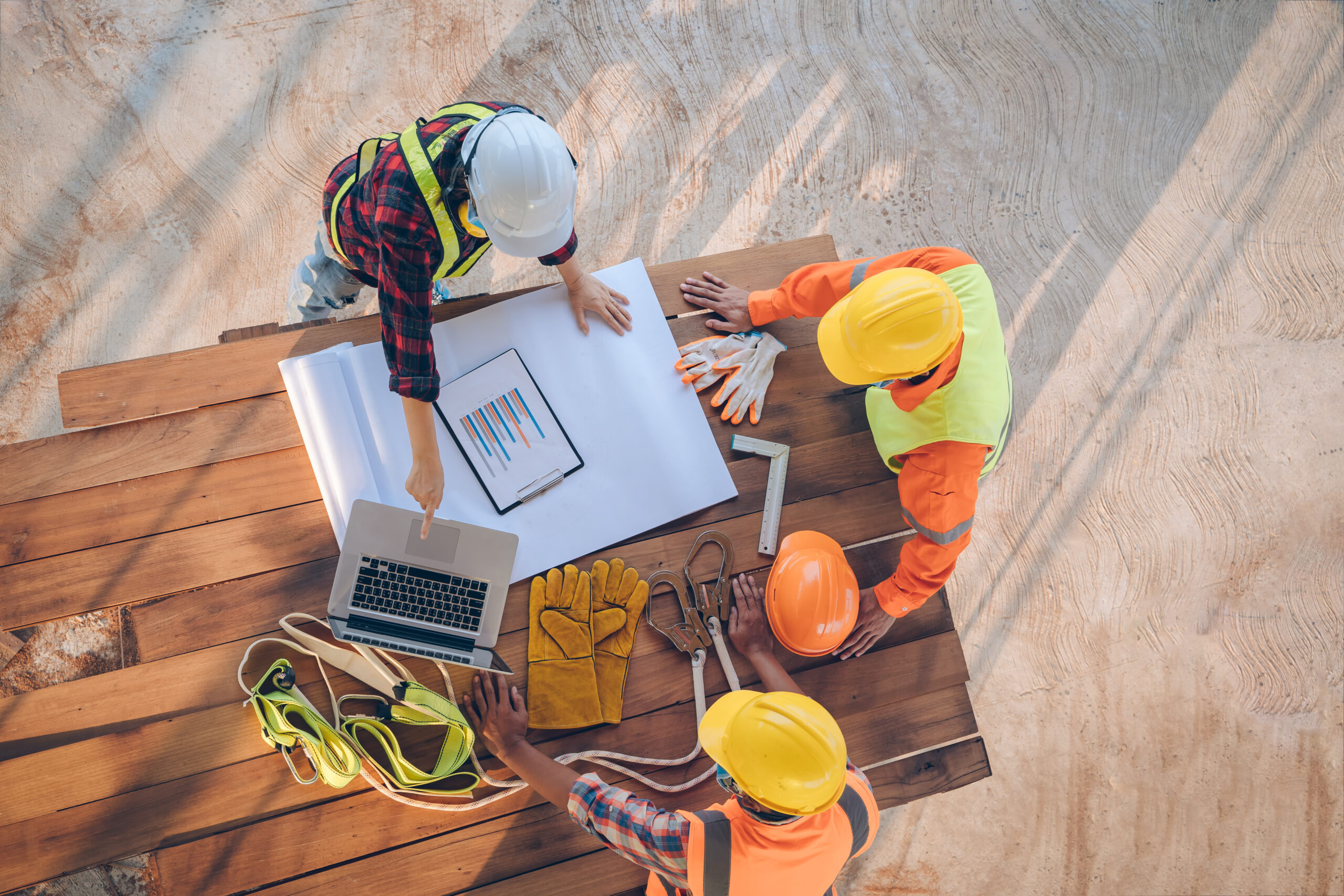 Three construction workers look at a laptop on the worksite.